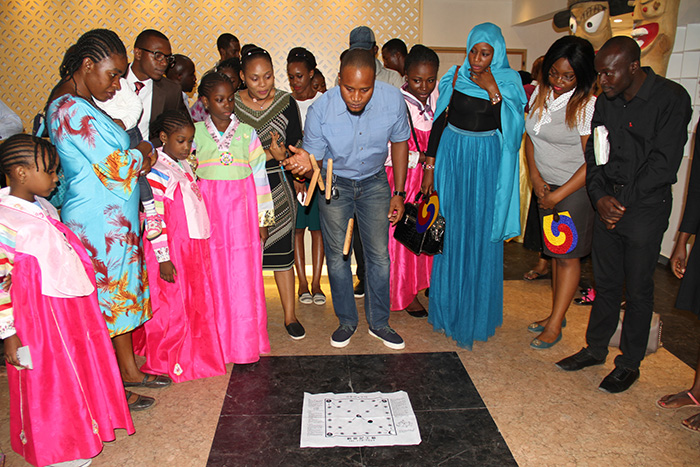 Guests at the Korean Cultural Centre in Nigeria try their hand at Korea's traditional four-stick board game, <i>yunnori</i> (윷놀이).